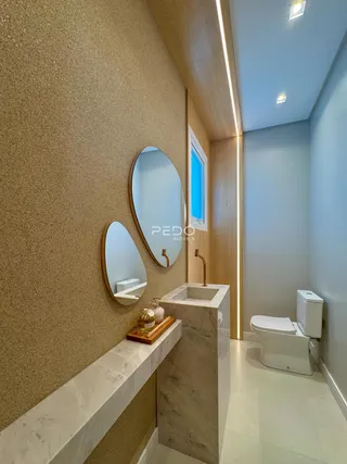 Interior de um banheiro moderno com bancada de mármore e espelhos.