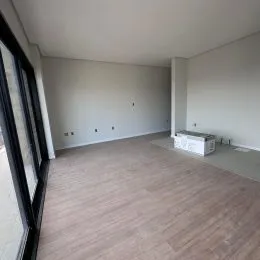 Foto de um ambiente interno amplo com paredes brancas e piso de madeira.