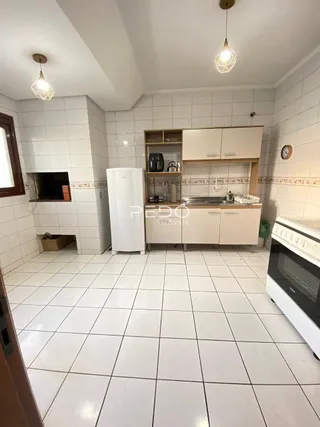 Interior de uma cozinha com revestimento cerâmico branco e armários.
