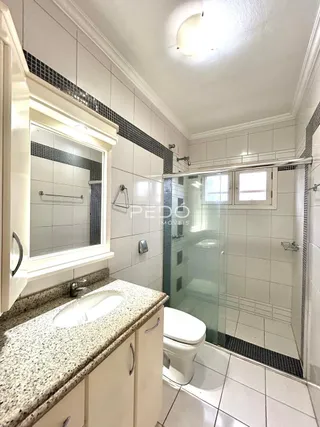 Foto de um banheiro com revestimento cerâmico e box de vidro.
