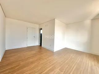 Ambiente interno amplo com piso de madeira clara e paredes brancas.