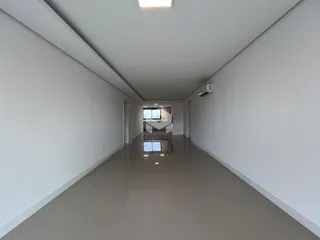 Corredor longo e iluminado com paredes brancas.