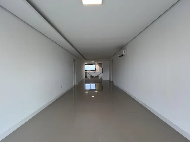 Corredor longo e iluminado com paredes brancas.