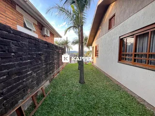 Vista externa da residência com muro de tijolos e gramado verde.
