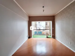 Sala de estar com piso de madeira clara e acesso a uma área externa.