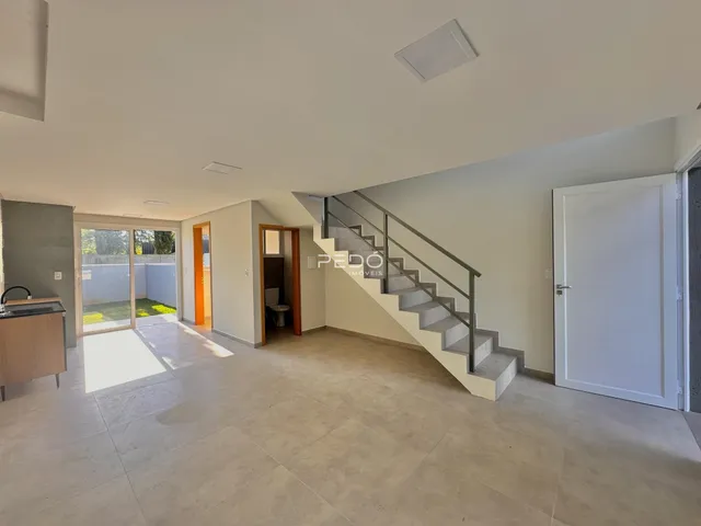 Ambiente interno de uma sala de estar com piso de cerâmica e escadaria.