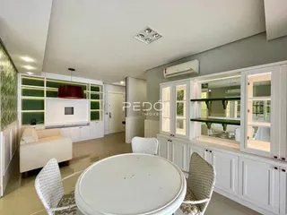 Sala de estar com cozinha integrada e armários brancos.