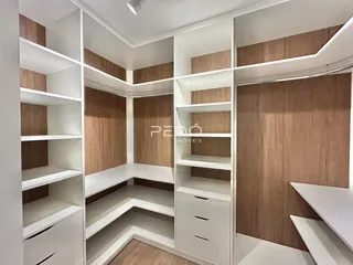 Ambiente interno com estantes e armários embutidos em tom de madeira clara.
