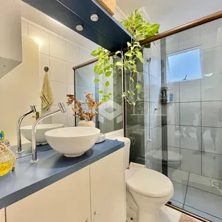 Banheiro moderno com bancada azul e box de vidro.