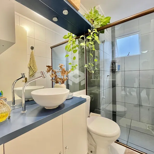 Banheiro moderno com bancada azul e box de vidro.