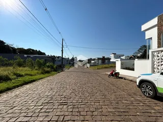 Vista da rua pavimentada em Lajeado, Brasil, com residências ao fundo.