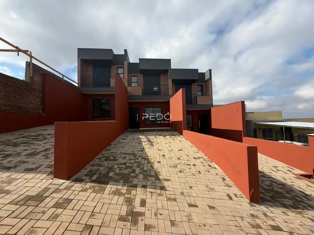 Fachada de uma residência com paredes vermelhas e pátio pavimentado.