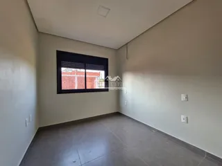 A sala apresenta paredes brancas e um piso de concreto.