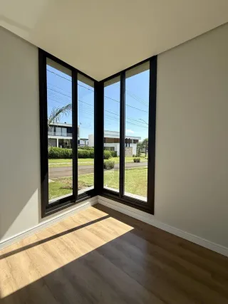 Sala de estar com piso de madeira e grandes janelas que dão vista para o exterior.