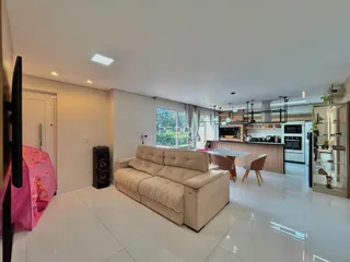 Sala de estar moderna com cozinha integrada e piso de cerâmica clara.