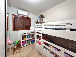Um quarto com estantes brancas cheias de brinquedos e um armário de madeira.
