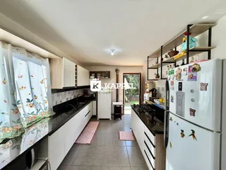 Cozinha moderna com armários brancos e bancadas escuras.