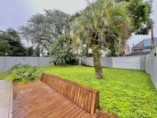 Vista externa de um quintal com gramado verde e deck de madeira.
