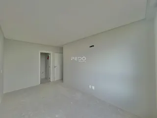 Vista interna de um ambiente vazio com paredes brancas e piso de concreto.