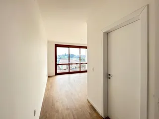 Hall de entrada com piso de madeira clara e porta de vidro que oferece uma vista externa.