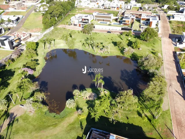 Vista aérea de uma propriedade com um lago cercado por gramado e árvores.