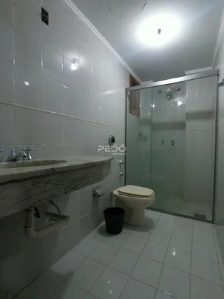 Foto de um banheiro com revestimento cerâmico e box de vidro.
