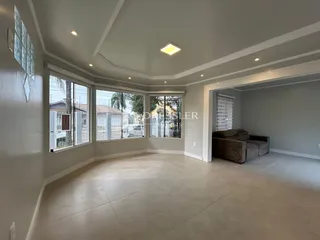 Sala de estar com grandes janelas e teto alto em imóvel no Brasil.