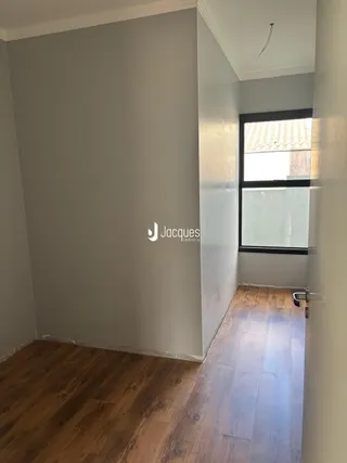 Hall de entrada com piso de madeira e parede clara.