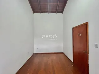 Interior de uma sala com piso de madeira e parede branca.
