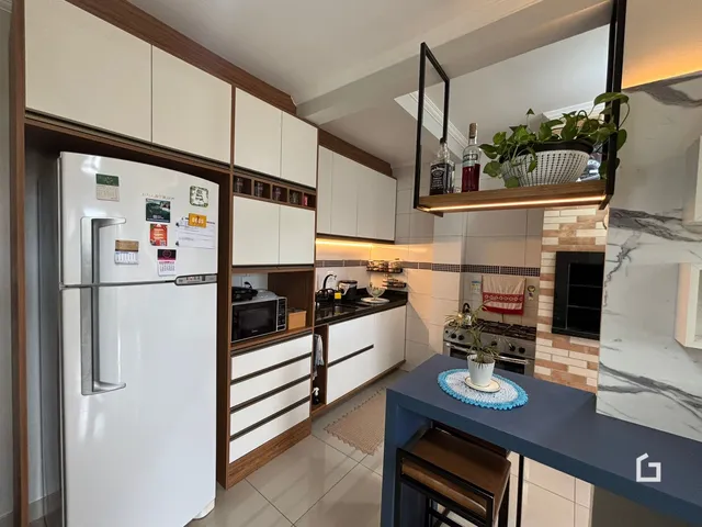 Cozinha moderna com armários brancos e bancada escura.