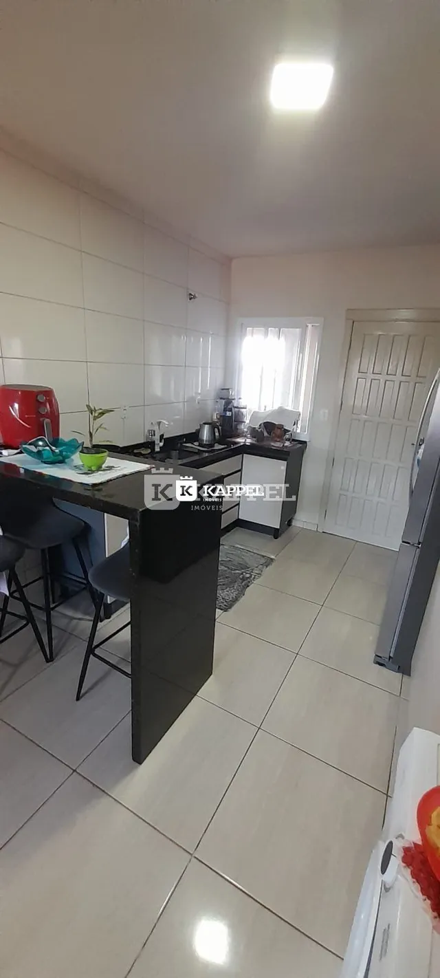 Esta é uma foto da cozinha com bancadas escuras e eletrodomésticos.