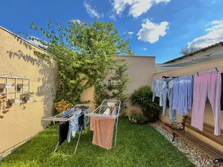 Vista externa de um quintal gramado com roupas penduradas contra uma parede.