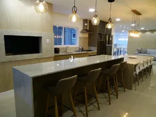 Vista da cozinha com ilha e banquetas de madeira.