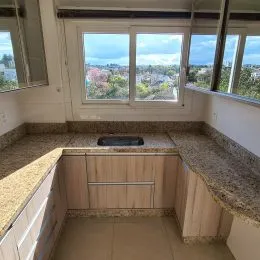 Bancada e armários de madeira são visíveis em uma área interna da propriedade.
