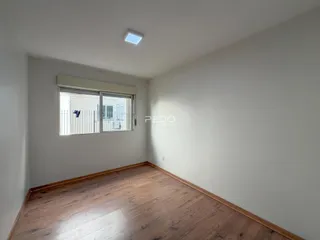 Ambiente interno de uma sala com piso de madeira e janela.