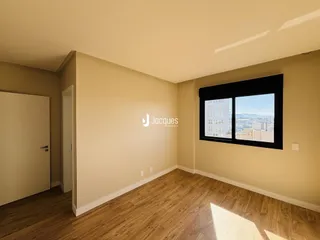 Ambiente interno de uma sala com piso de madeira e janela.