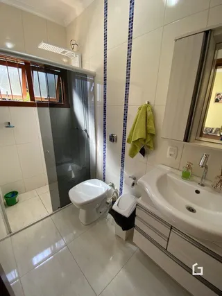 Foto de um banheiro com azulejos brancos e piso de cerâmica.