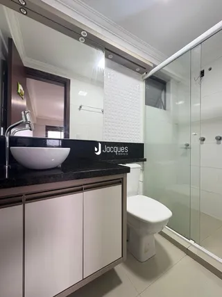 Foto de um banheiro moderno com bancada escura e box de vidro.