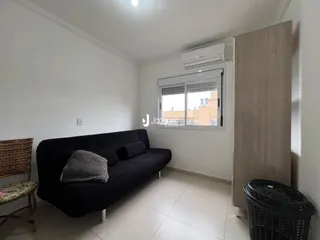 Sala de estar com sofá escuro e janela de boa iluminação.