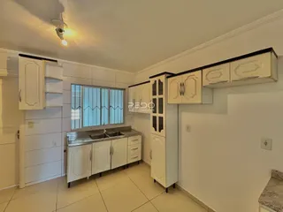 Vista interna de uma cozinha com armários brancos e piso claro.