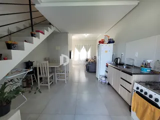 Interior de uma sala de estar com cozinha e área de jantar em um imóvel no Brasil.
