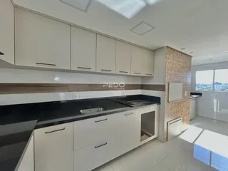 Cozinha moderna com armários brancos e bancadas escuras.