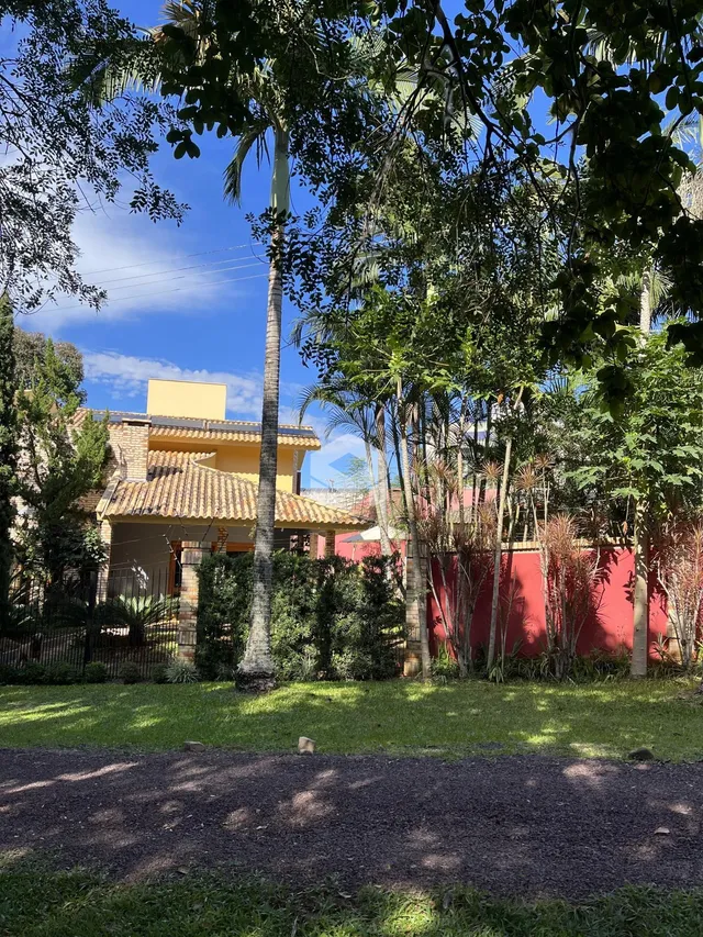 Fachada de uma residência em Lajeado, Brasil, com vegetação densa na frente.