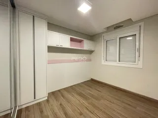 Ambiente interno com piso de madeira e armários brancos.
