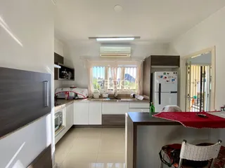 Interior de uma cozinha moderna com janelas e armários brancos.