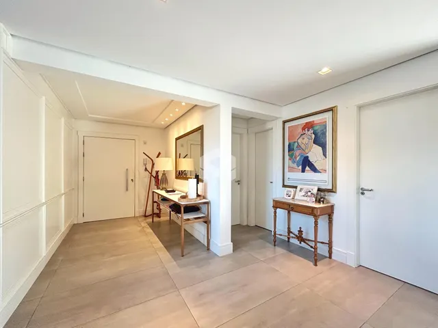 Hall de entrada com piso de madeira clara e paredes brancas.