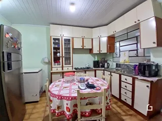 Foto de uma cozinha com armários e mesa de jantar em uma residência.