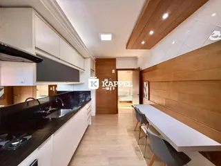 Cozinha moderna com armários brancos e bancada preta em um ambiente bem iluminado.