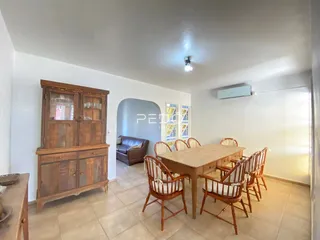 Sala de jantar com mesa de madeira e armário no interior da residência.