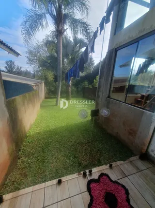 Vista do quintal com gramado e deck de madeira.
